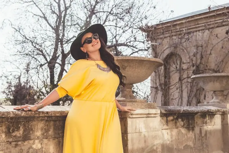 woman in yellow dress, hat, and shades